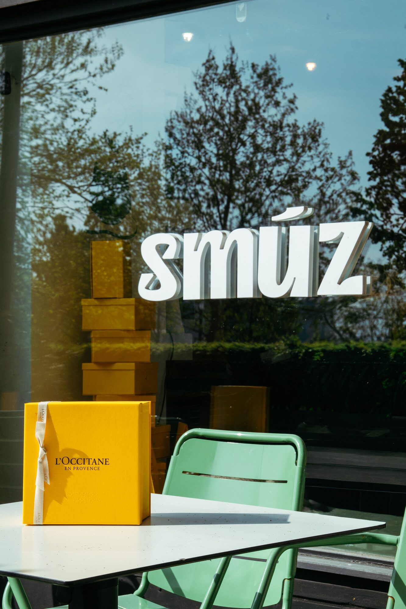 Smúz Café Budapest window logo and L'Occitane yellow gift boxes on the terrace